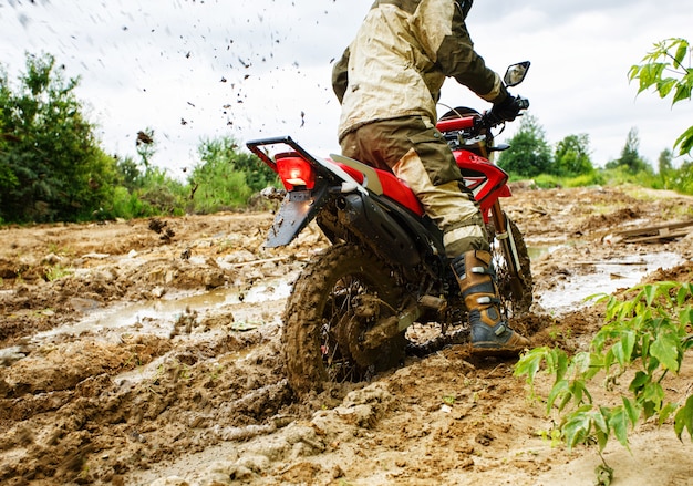 L'homme à moto roule dans la boue
