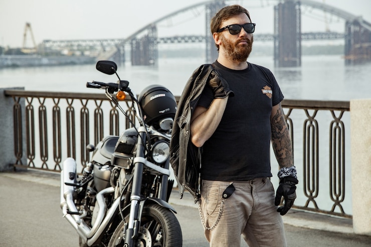 Photo homme motocycliste barbu avec sa moto sur la pose d'été.