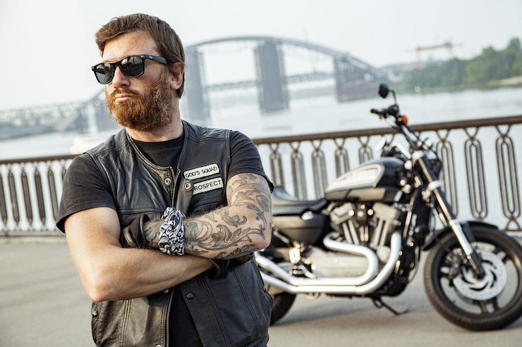 Photo homme motocycliste barbu avec sa moto sur la pose d'été.