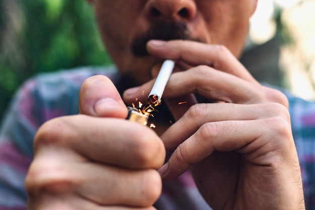 Homme avec moustache et barbe allumant une cigarette