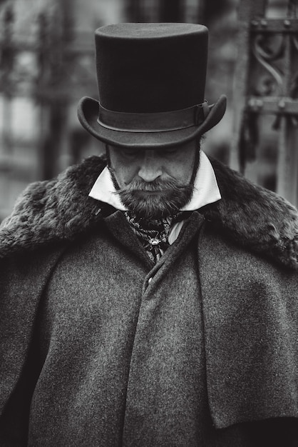 Homme moustachu respectable dans des vêtements rétro classiques, un manteau et un chapeau.