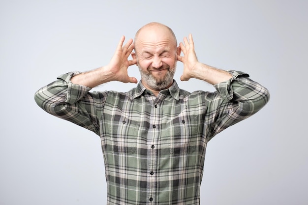 Homme mûr agacé boucher les oreilles avec les doigts