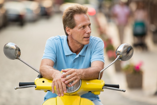 Homme mûr assis sur un scooter.