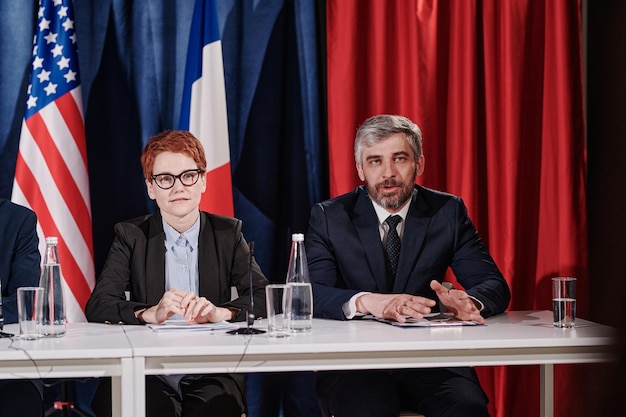 Homme mûr aux cheveux gris donnant son rapport à la conférence alors qu'il était assis à table avec son collègue