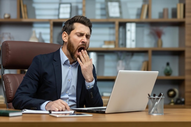 Homme mûr bâillant à l'intérieur d'un bureau classique homme d'affaires senior en milieu de travail sans sommeil et surmené