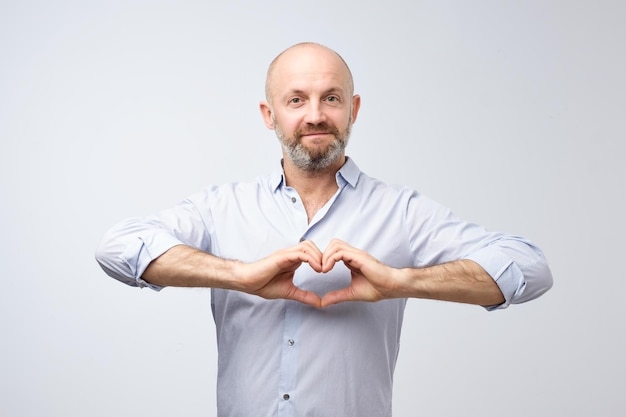 Homme mûr avec barbe faisant du coeur des mains