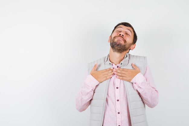 Homme mûr en chemise, veste sans manches avec les mains sur la poitrine et l'air satisfait, vue de face.