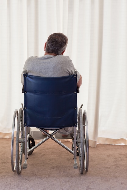 Homme mûr dans son fauteuil roulant avec son dos à la caméra