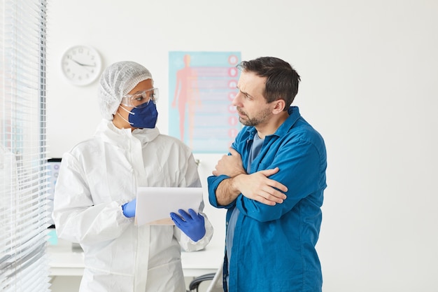 Homme mûr écoutant attentivement l'infirmière pendant qu'elle parle de la prescription de médicaments au bureau