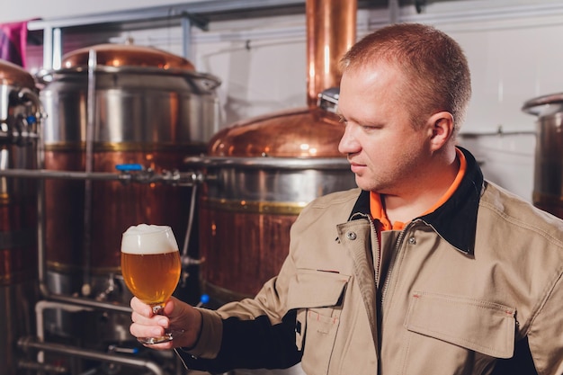 Photo homme mûr examinant la qualité de la bière artisanale dans une brasserie inspecteur travaillant dans une usine de fabrication d'alcool vérifiant la bière homme dans une distillerie vérifiant le contrôle de la qualité de la bière de tirage