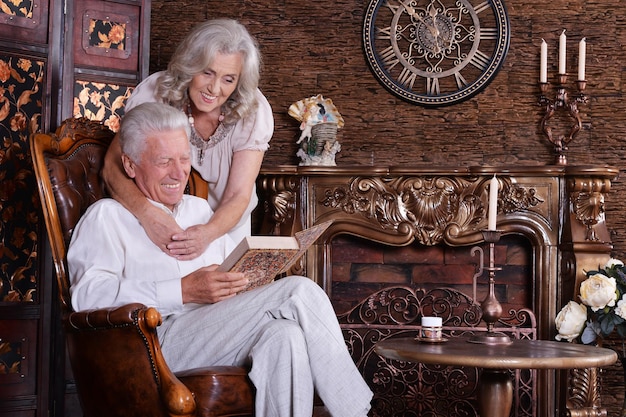 Homme mûr et femme lisant un livre dans une chambre avec un intérieur vintage