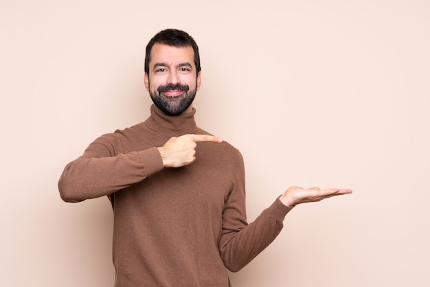 Homme sur mur isolé tenant une surface imaginaire sur la paume pour insérer une annonce