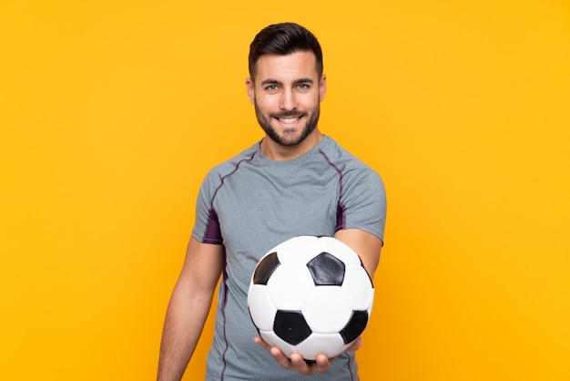 Homme sur mur jaune isolé avec ballon de foot