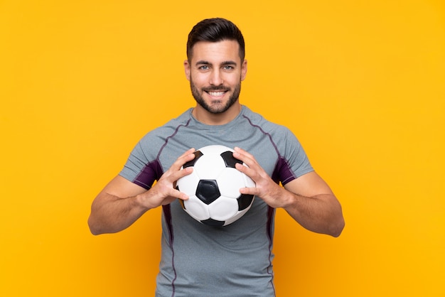 Homme sur mur jaune isolé avec ballon de foot