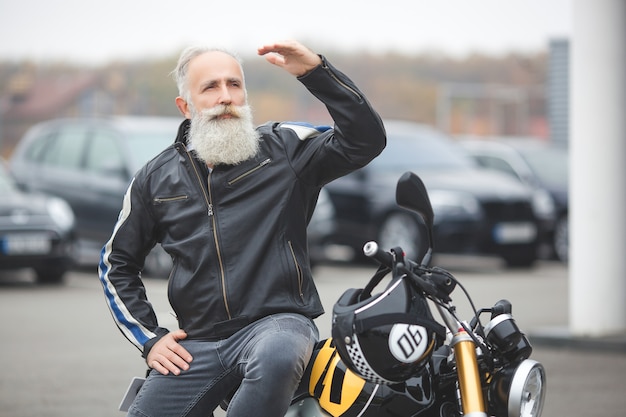 Homme mûr sur une moto. Vieux mâle sur moto. Homme barbu conduisant à l'extérieur.