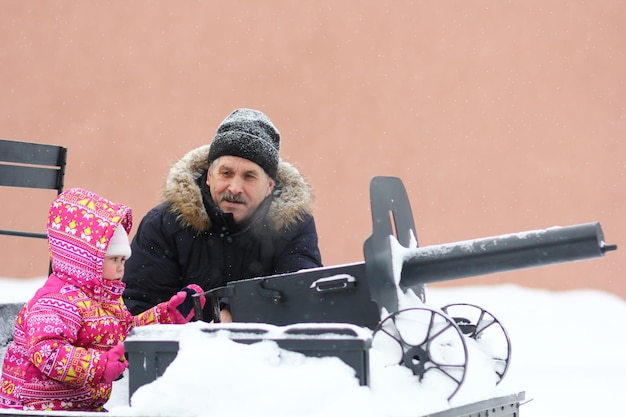 Homme mûr et petite fille sur le monument de tachanka dans le parc enneigé en hiver