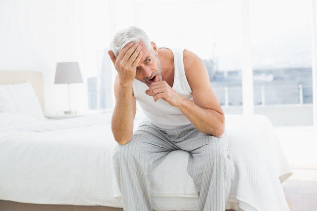 Homme mûr réfléchi bâillement dans son lit