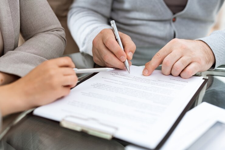 Homme mûr avec un stylo va signer un contrat ou un autre document financier après avoir négocié avec l'agent