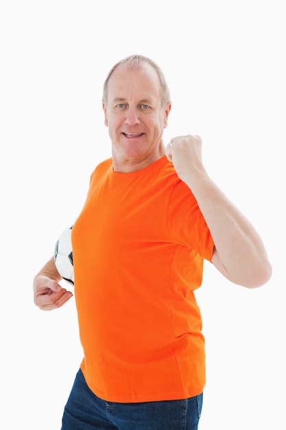 Homme mûr en tshirt orange acclamant tenant le football