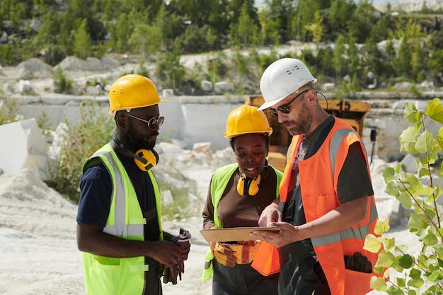 Homme mûr en vêtements de travail pointant vers l'écran de la tablette pendant la présentation