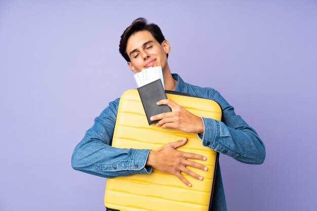 Homme sur mur violet isolé en vacances avec valise et passeport