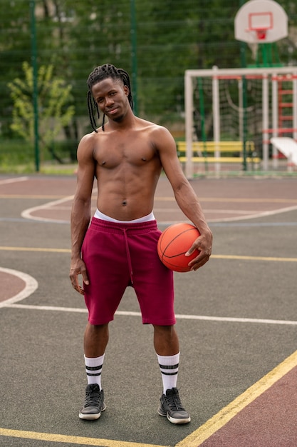 Homme Musclé Africain Torse Nu Avec Ballon Debout Sur Un Terrain De Basket Ou Un Stade Après L'entraînement