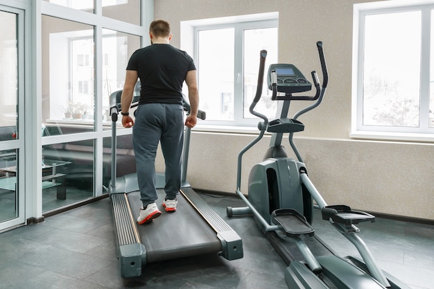 Homme musclé athlétique en cours d'exécution sur des tapis roulants