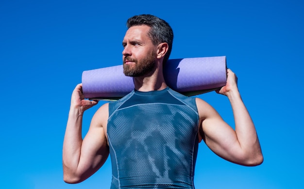 Homme musclé athlétique tenir fitness tapis de yoga