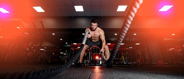 Homme musclé attrayant travaillant avec des cordes lourdes Photo de bel homme Mise au point sélective du concept Crossfit avant