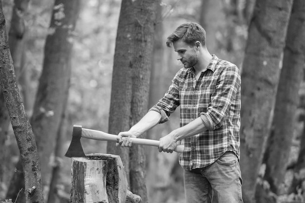 Homme musclé en chemise à carreaux avec hache dans l'activité masculine de la forêt