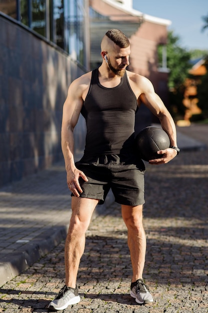 Homme musclé ou entraîneur de fitness avec ballon de poids fitness à l'extérieur