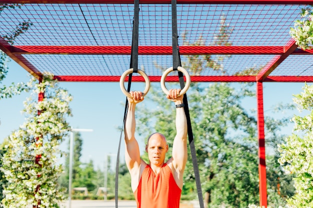 Homme musclé exerçant avec des anneaux.