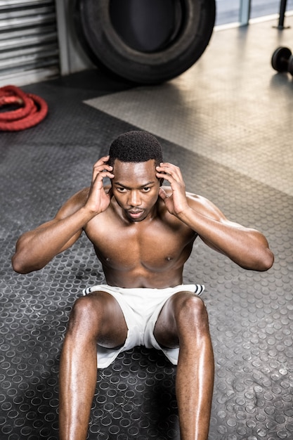 Homme musclé faisant des abdominaux dans la salle de gym crossfit