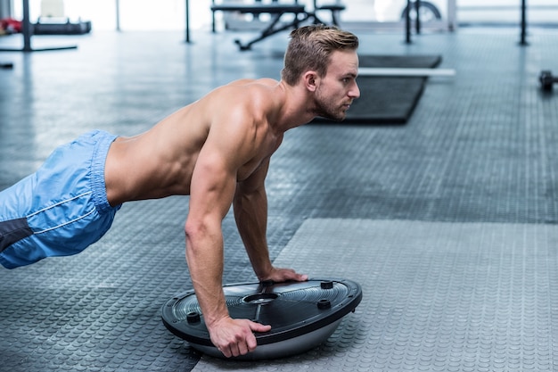 Homme musclé faisant des exercices de balle de bosu