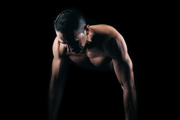 Homme musclé faisant des pompes avec fond noir