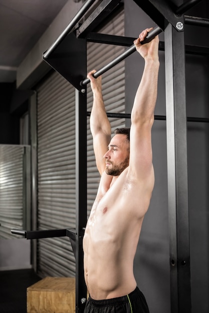 Homme musclé faisant pull up au gymnase de crossfit