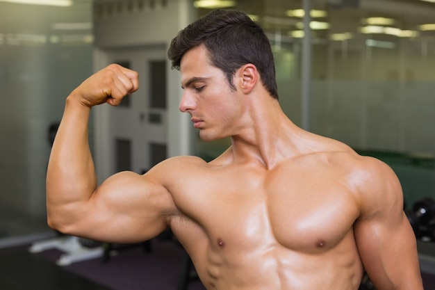 Homme musclé, flexion des muscles dans la salle de gym