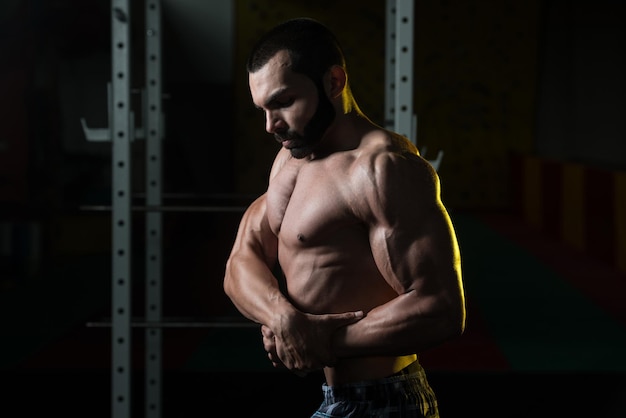 Homme musclé, flexion des muscles dans la salle de gym