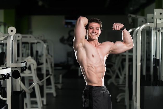 Homme musclé, flexion des muscles dans la salle de gym
