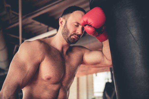 Homme musclé en gants de boxe pratique.