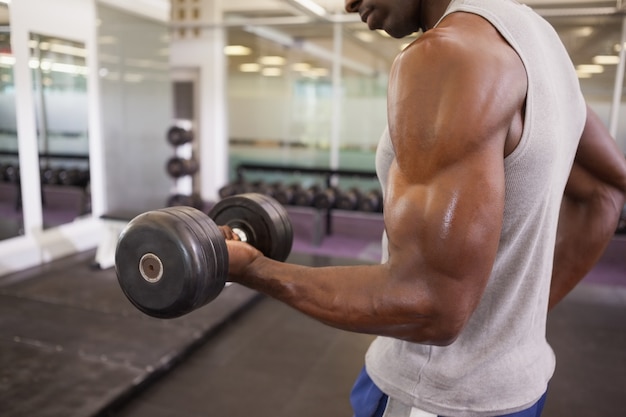 Homme musclé avec haltère dans la salle de gym