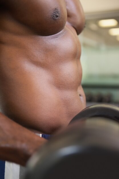 Homme musclé avec haltère dans la salle de gym