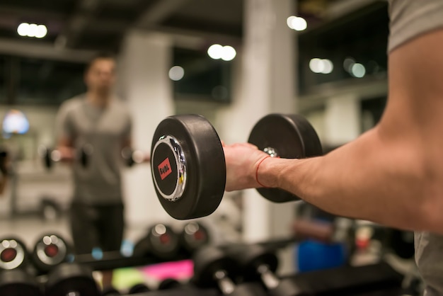 Homme musclé avec haltère rouge de formation dans la salle de gym