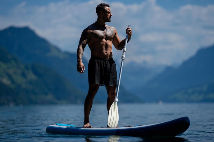 Photo un homme musclé avec une planche à pagaie un homme à la planche à gaine un homme muscleux et fort un homme hispanique sur une planche de sup