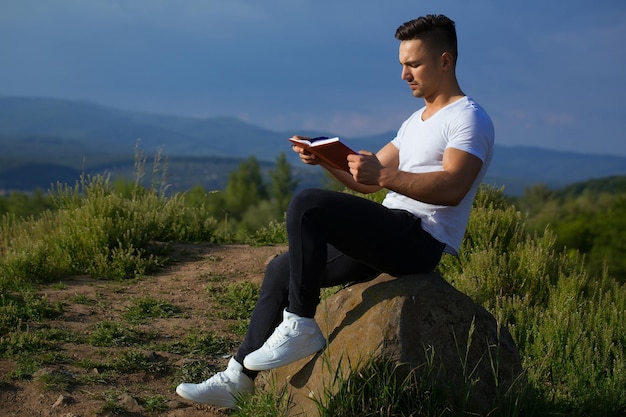 Homme musclé songeur avec livre en plein air