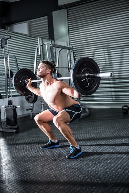 Homme musclé soulevant une barre