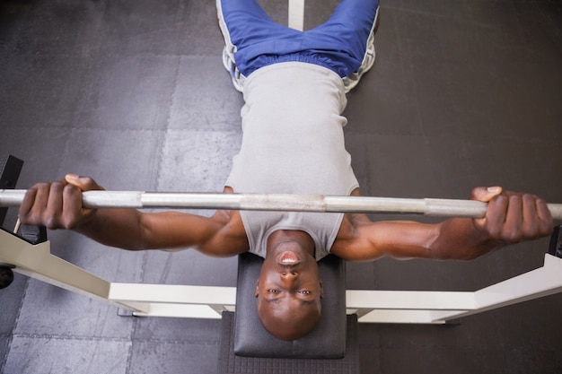 Homme musclé, soulevant des haltères dans la salle de gym