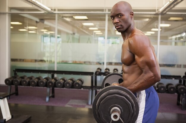 Homme musclé, soulevant des haltères dans la salle de gym