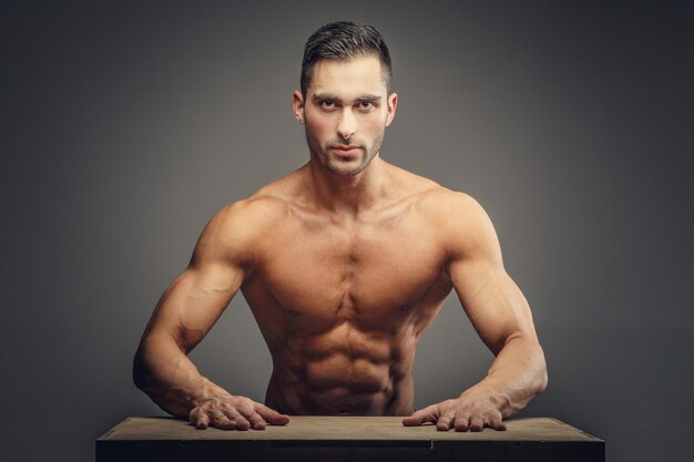 Homme musclé torse nu en jeans. Isolé sur fond gris.