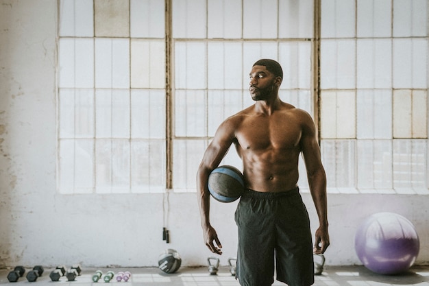 Homme musclé torse nu tenant un ballon de fitness